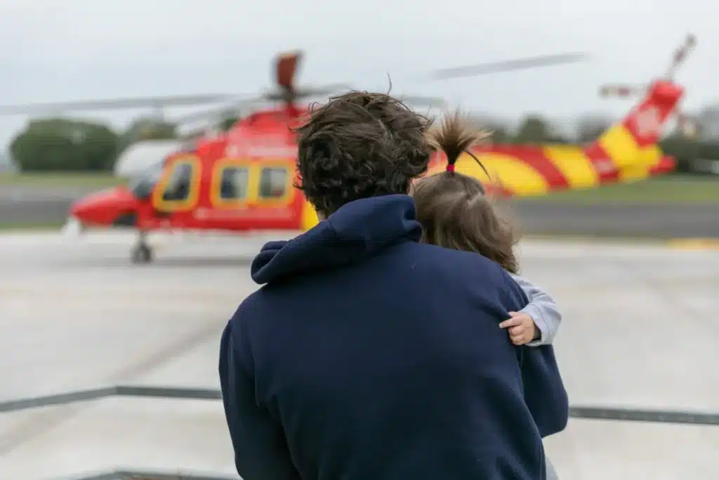 Patient Visit, father holding daughter as they watch the helicopter