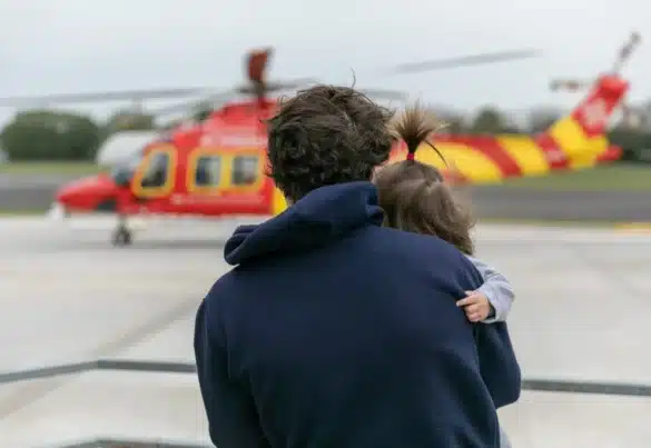 Patient Visit, father holding daughter as they watch the helicopter