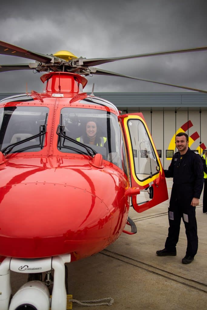 Pilot Will at the front of the AW169 with a visitor in the pilot seat