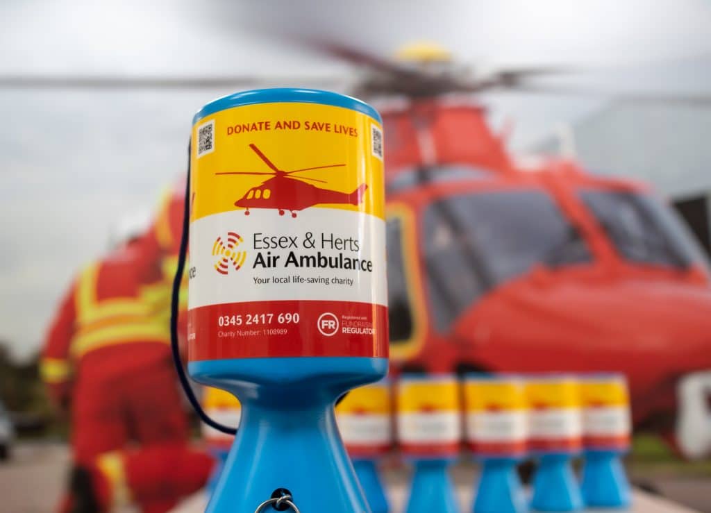 Community collection tins in front of helicopter and crew backdrop